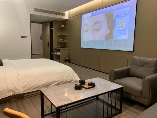 a room with a bed and a couch and a screen at New Century Mansion Hotel Cixi Guanhaiwei in Cixi