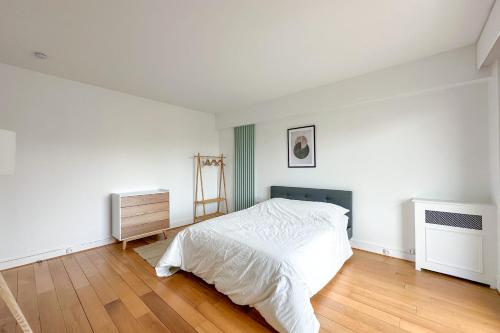 une chambre blanche avec un lit et un parquet dans l'établissement Flexliving - sublime flat - Ternes, à Paris