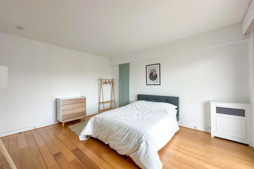 une chambre blanche avec un lit et un parquet dans l'établissement Flexliving - sublime flat - Ternes, à Paris