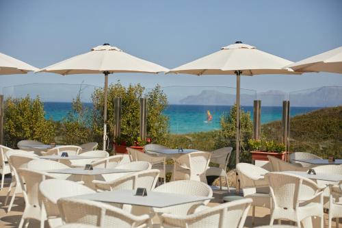 a row of tables and chairs with umbrellas and the ocean at Playa Esperanza Resort Affiliated by Meliá in Playa de Muro