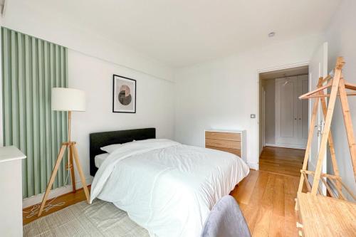 - une chambre blanche avec un lit et une échelle dans l'établissement Flexliving - room - Ternes, à Paris