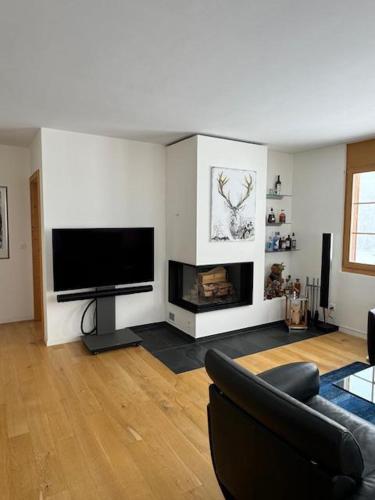 ein Wohnzimmer mit einem Flachbild-TV und einem Kamin in der Unterkunft Design Flat Davos in Davos