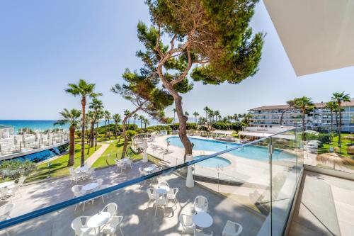 a balcony with a view of a pool and the ocean at Playa Esperanza Resort Affiliated by Meliá in Playa de Muro