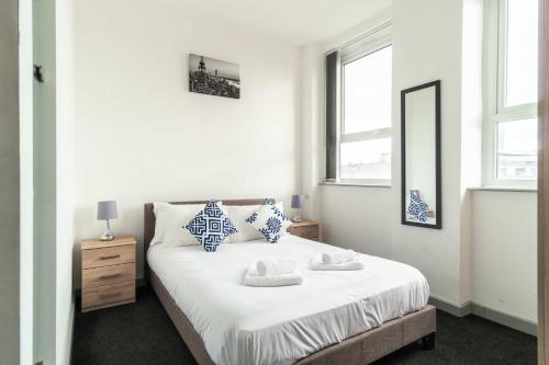 a bedroom with a bed with a mirror and two windows at Fabulous 1 Bed Apartment in Central Blackburn in Blackburn