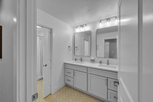 a white bathroom with two sinks and two mirrors at Sunset Cove home in Oshkosh