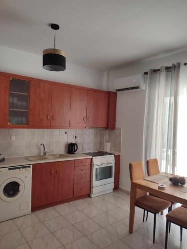 a kitchen with wooden cabinets and a table and a sink at One Bedroom Flat 300m from Sea in Alexandroupoli