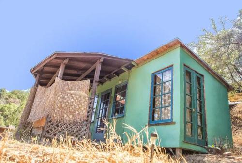 a small green house sitting on top of a field at Backpacker's Dream with detached bathroom, private trails and creek! in Topanga Park