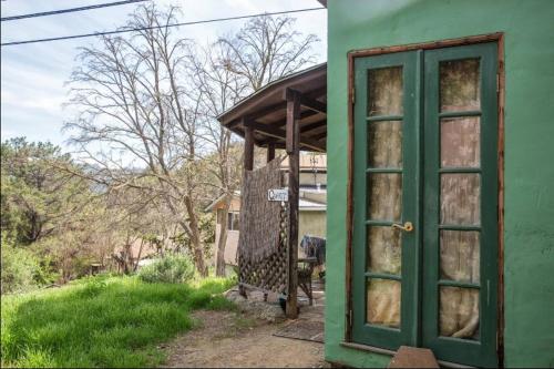 a green door on the side of a house at Backpacker's Dream with detached bathroom, private trails and creek! in Topanga Park