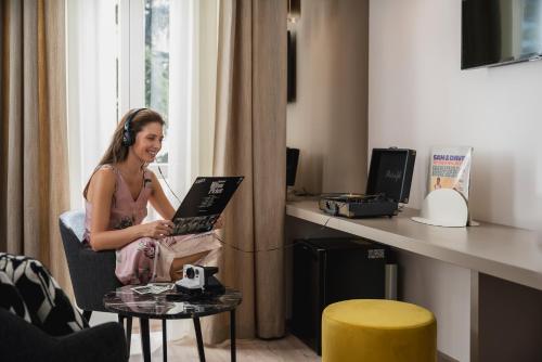 a woman sitting in a chair with a laptop at Hotel Helvetia Thermal SPA 4s in Porretta Terme