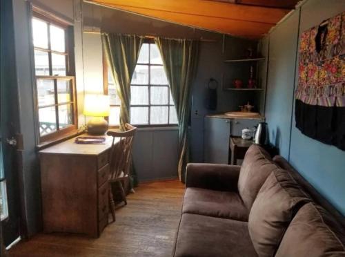 a living room with a couch and a table and windows at Backpacker's Dream with detached bathroom, private trails and creek! in Topanga Park