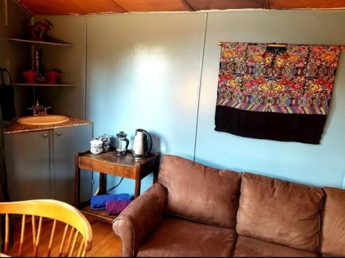 a living room with a brown couch and a table at Backpacker's Dream with detached bathroom, private trails and creek! in Topanga Park