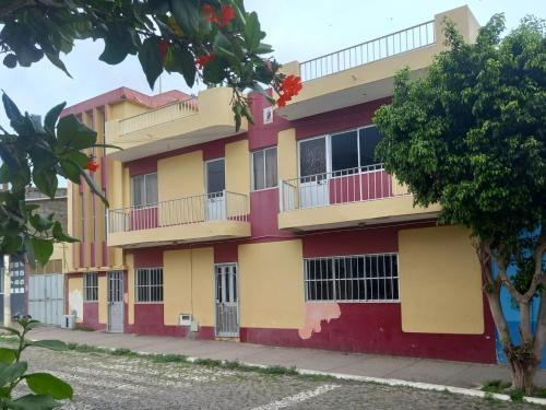 a yellow and red building with a tree at Casa Mario in Tarrafal
