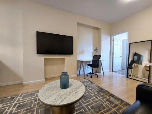 a living room with a table and a tv at Comfortable Apartment with Workstation in New York
