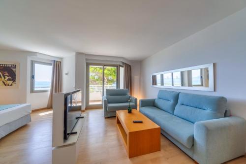 a living room with a blue couch and a tv at Playa Esperanza Resort Affiliated by Meliá in Playa de Muro