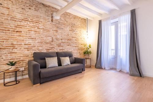 a living room with a couch and a brick wall at Cavallers Suites - Unik Vacation in Tarragona