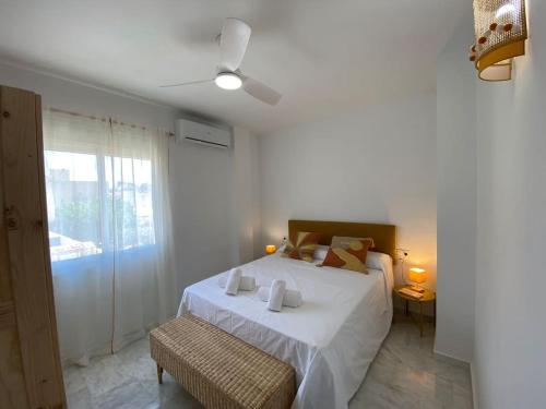 een witte slaapkamer met een bed en een plafondventilator bij Dúplex Romero y Alba in Sanlúcar de Barrameda