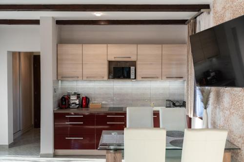 a kitchen with wooden cabinets and a table with chairs at Villa Garden in Zalaegerszeg