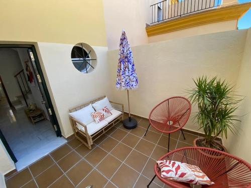 een patio met 2 stoelen, een tafel en een parasol bij Dúplex Romero y Alba in Sanlúcar de Barrameda