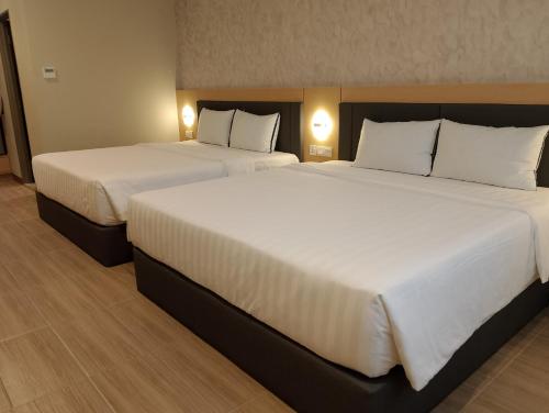 two beds in a hotel room with white sheets and pillows at Forum Hotel Penang in George Town
