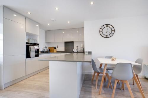 a kitchen with white cabinets and a white table and chairs at St Martins 2 Bedroom Apartments in Ruislip By 360 Stays in Ruislip