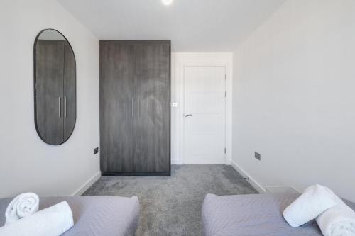 a bedroom with a bed and a mirror and a door at St Martins 2 Bedroom Apartments in Ruislip By 360 Stays in Ruislip