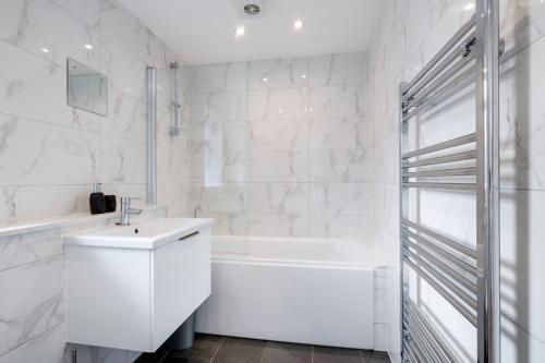 a white bathroom with a sink and a bath tub at St Martins 2 Bedroom Apartments in Ruislip By 360 Stays in Ruislip