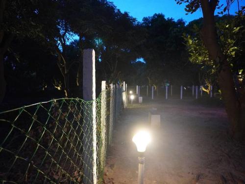 a fence with a light in a cemetery at night at Ess Emm Farms in Vasavasamudram