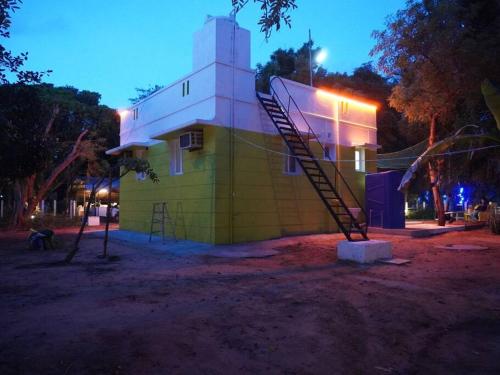 a small yellow building with a spiral staircase in front of it at Ess Emm Farms in Vasavasamudram