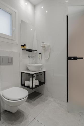 a white bathroom with a toilet and a sink at Piraeus City Hotel in Piraeus