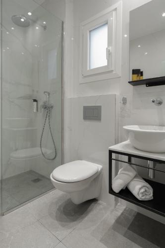 a white bathroom with a toilet and a sink at Piraeus City Hotel in Piraeus