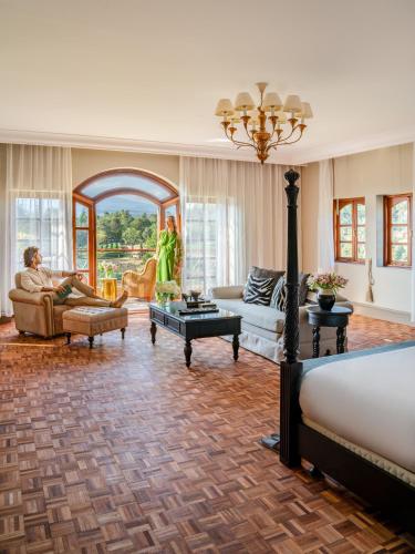 a living room with a man sitting on a couch at Fairmont Mount Kenya Safari Club in Nanyuki