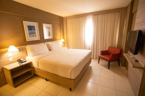 a hotel room with a bed and a red chair at Hilton Garden Inn Maceio in Maceió