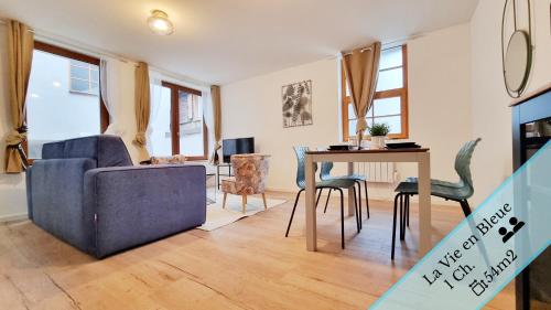 un salon avec un canapé bleu et une table dans l'établissement Les Appartements Charme et Élégance, à Sainte-Croix-en-Plaine