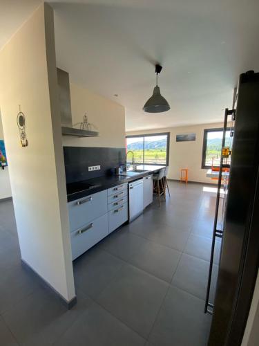a kitchen with white cabinets and a large window at Rev'ôthijol Vacances in Saint Alban Auriolles