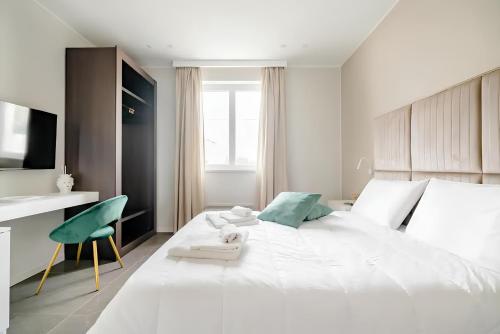 a white bedroom with a large bed and a chair at Shoruq in Marsala