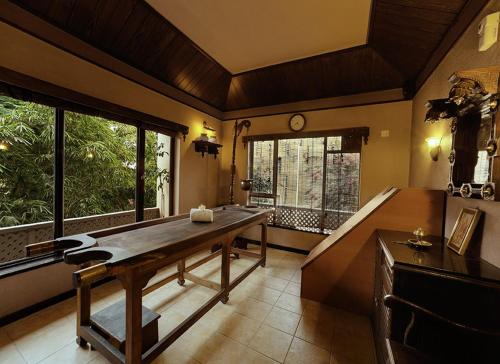 a dining room with a wooden table and windows at Renest Shraddha Inn - Shirdi in Shirdi