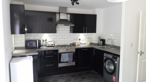 una cucina con armadi neri e una lavatrice/asciugatrice di 3 bed house Market Deeping - Peterborough, Stamford, Spalding a Market Deeping