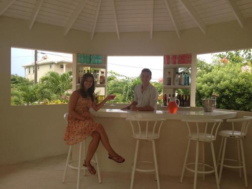 a man and a woman sitting at a bar at Holland Park Barbados in Saint Peter