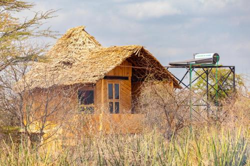 a house with a thatch roof with a sign on it at Olemayian Amboseli Cottages in Kimana