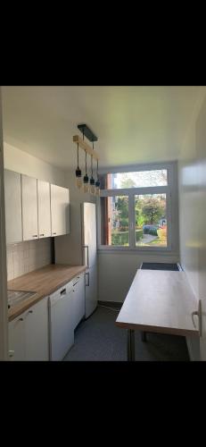 une cuisine avec des armoires blanches, une table et une fenêtre dans l'établissement Charmant appartement au calme, à Maisons-Laffitte