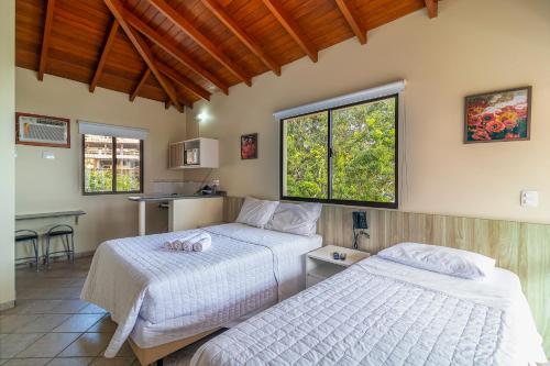 a bedroom with two beds and a table and a kitchen at Stúdio Jurerê vista Mar in Florianópolis
