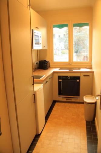 une petite cuisine avec un évier et un micro-ondes dans l'établissement Appartement Élégant avec Balcon Centre Cannes, à Cannes