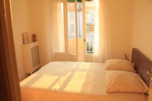 un grand lit dans une chambre avec une fenêtre dans l'établissement Appartement Élégant avec Balcon Centre Cannes, à Cannes