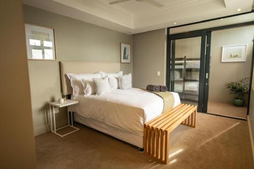a bedroom with a large bed and a wooden bench at Ocean Family Deluxe, Hermanus Waterfront - Apt 2 in Hermanus