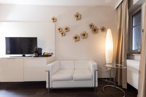 a living room with a white chair and a tv at Maiers Kuschelhotel Loipersdorf - ADULTS ONLY in Loipersdorf bei Fürstenfeld