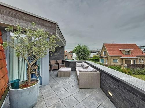 a patio with a couch and chairs on a balcony at Villa Alice - Sint-Idesbald in Koksijde