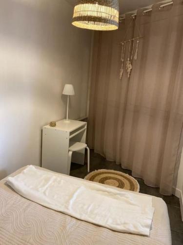 une chambre avec un lit, un bureau et un lustre dans l'établissement Appartement proche conservatoire hyper centre, à Reims