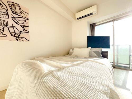 a bedroom with a white bed with a painting on the wall at Shinjuku City, 2 Double Beds Apt, Free WiFi in Tokyo