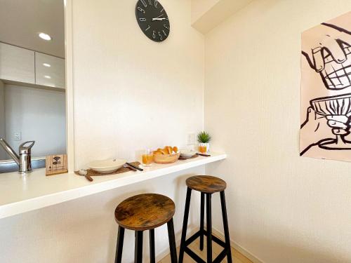 a kitchen with two stools and a clock on the wall at Shinjuku City, 2 Double Beds Apt, Free WiFi in Tokyo