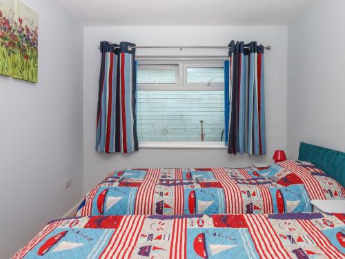 a bedroom with a bed and a window with curtains at Brixham Breeze Cabin in Brixham